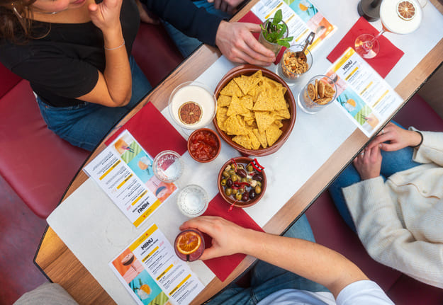 A overhead shot of a table with cocktails and snacks on it