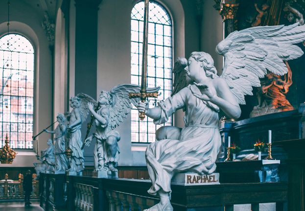 Angel sculptures inside the Church of Our Lady in Copenhagen with marble figures and tall arched windows
