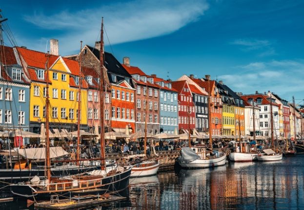 Colorful houses and wooden boats lining canal in Nyhavn in Copenhagen.