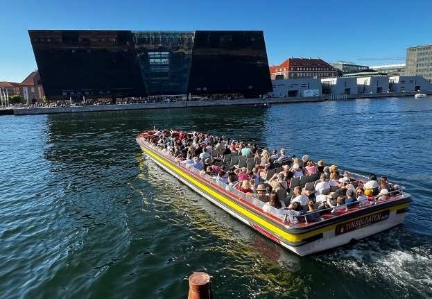 Kanalboot mit Touristen fährt vor dem Bibliotheksgebäude Den Sorte Diamant im Hafen von Kopenhagen