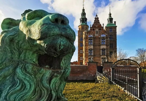 Close-up of a lion statue with Rosenborg Castle visible in the background