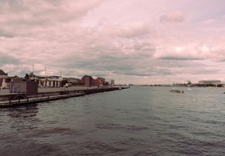 Udsigt over Ofelia Plads og Københavns havn med bygninger ved vandet og skyet himmel