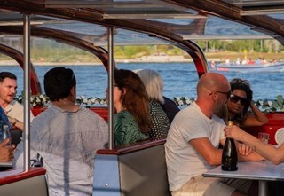 Gäste genießen eine entspannte Bootsfahrt mit Prosecco in Kopenhagen, umgeben von Blumenschmuck und Meeresblick.
