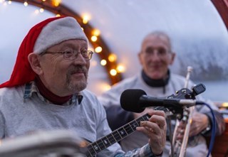 Man wearing a santa hat while playing a guitar.