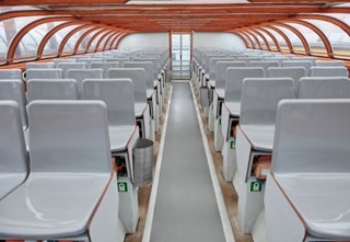 Rows of grey seats inside a covered canal boat with a curved glass roof