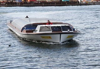 Covered canal boat with glass roof sailing in Copenhagen with a captain at the helm