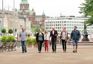 Tour guide with a group of customers in the Esplanade park. The Havis Amanda fountain and Uspenski Cathedral can be seen in the background.