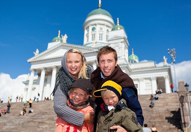 Kahden aikuisen ja kahden lapsen perhe seisoo Helsingin tuomiokirkon edessä.