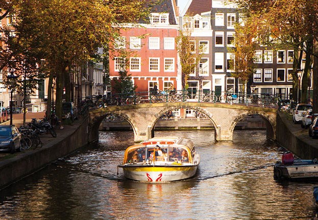Rondvaart door een smallere Amsterdamse gracht met oranje bomen