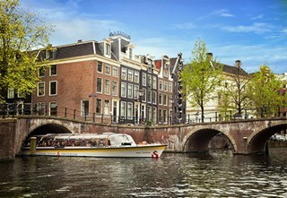 A Stromma sightseeing boat passing under a bridge on the canals of Amsterdam