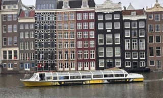 Amsterdam Dance Event official branded canal boat cruising past historic canal houses in Amsterdam
