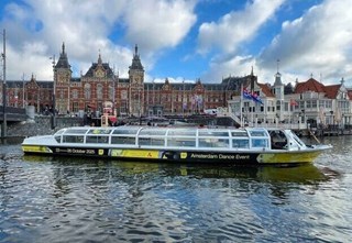 Amsterdam Dance Event-boot met het Centraal Station op de achtergrond.
