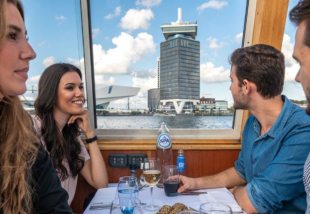 Group of friends having dinner on boat and looking at the A'DAM TOWER