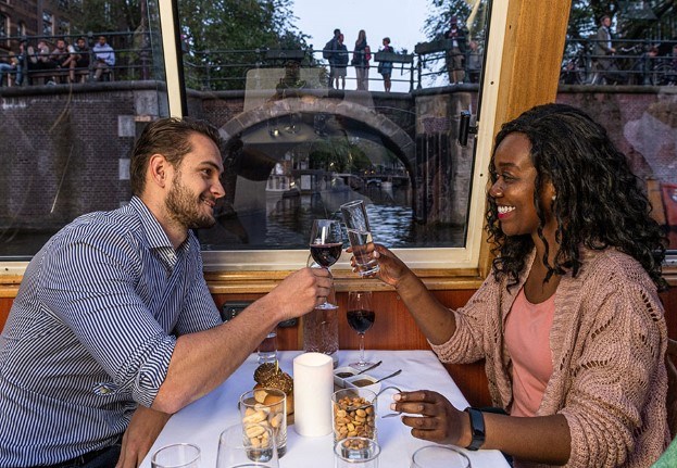 Couple on the boat toasts near a bridge in Amsterdam