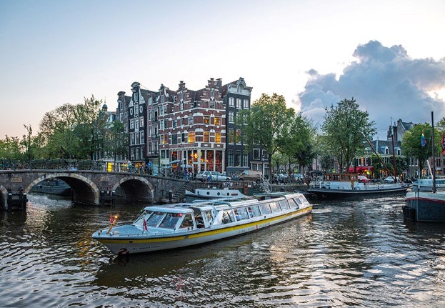 Rondvaartboot met Amsterdamse grachtenpanden in de achtergrond