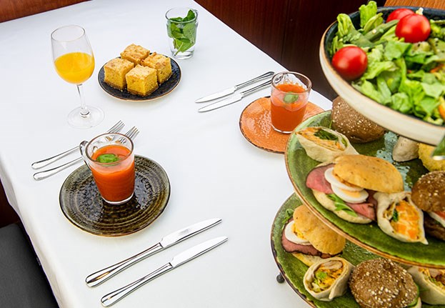 Tafel vol met verschillende broodjes, een salade, tomatensoep en jus d'orange