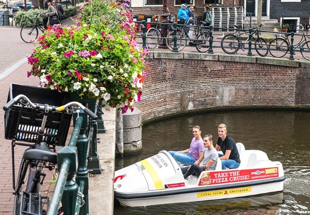 Jongens hebben plezier op een waterfiets terwijl ze over de Amsterdamse grachten cruisen 