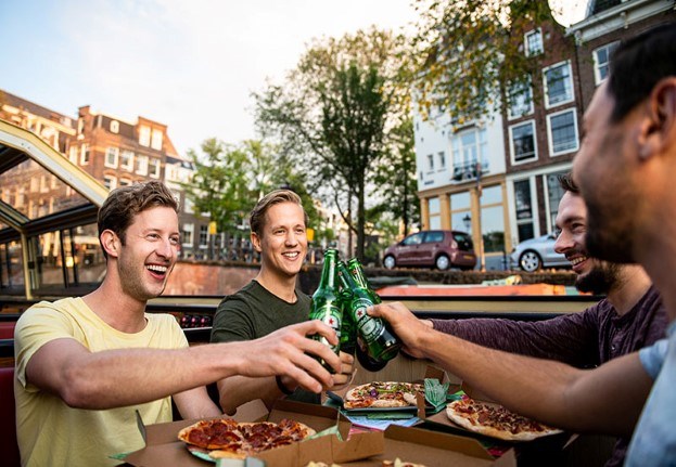 Vier gasten proosten met Heineken bier op de Pizza Cruise met goed weer