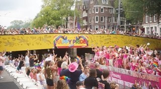 Mensen vieren Pride-kanaalparade in Amsterdam bij Stromma Anne Frank-locatie