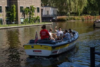 A group aboard a small sloop on a sunny day