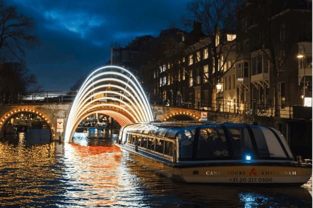 A Canal Tours Amsterdam Boat Going Towards An Archway Of Lights