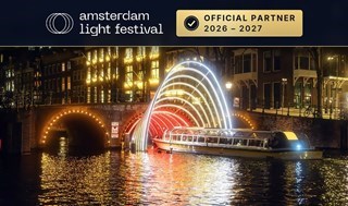Canal cruise boat from Stromma sailing underneath a bridge with lightart on it
