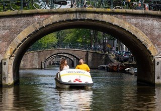 Couple biking underneath a couple of bridges with a pedal boat while enjoying their time together