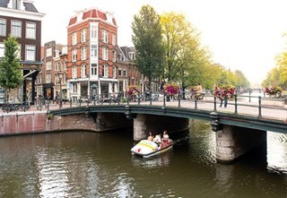 School friends are cruising the canals on a pedal boat while the sun goes down