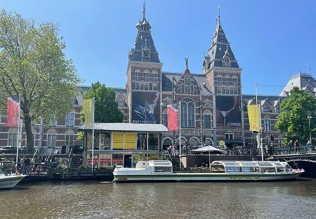 Stromma Rijksmuseum canal cruises departure point in Amsterdam, viewed from the water with the museum in the background.