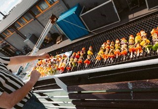 Person grilling colorful skewers on a sunny day aboard the boat MS Nobel
