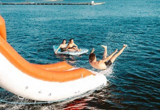 Man sliding down a waterslide on a dine and dip cruise in the Oslofjord 