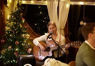 Musiker spiller gitar og synger ombord på M/S Nobel dekorert til jul.