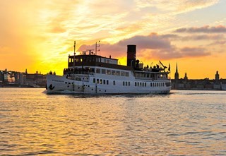 S/S Stockholm cruises in the Stockholm archipelago at dusk with calm waters and a beautiful evening sky.