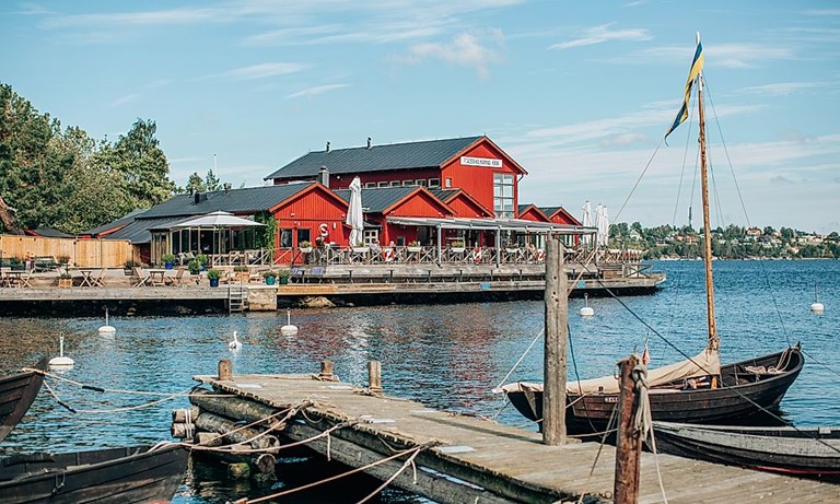 Fjäderholmarnas Krog – restaurang vid kajen med träbåtar. Båtutflykt till Fjäderholmarna, Stockholm.
