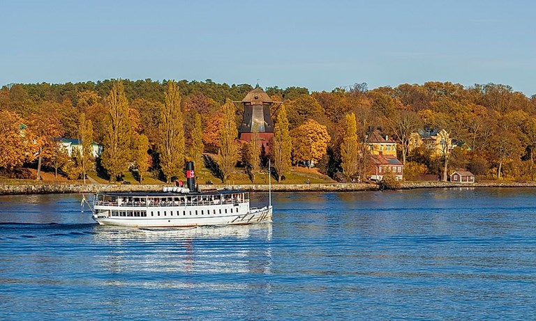 Utflyktsbåt passerar Vaxholm och höstfärger i Stockholms skärgård.