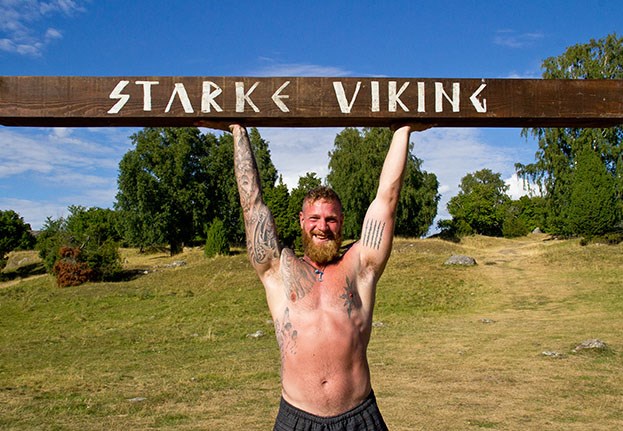 En viking håller upp en stock över huvudet med texten Starke Viking
