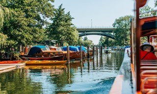 Canal boat passes a marina and bridge during sightseeing in Stockholm.