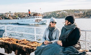 Två gäster njuter av kaffe på däck en solig vinterdag i Stockholm.