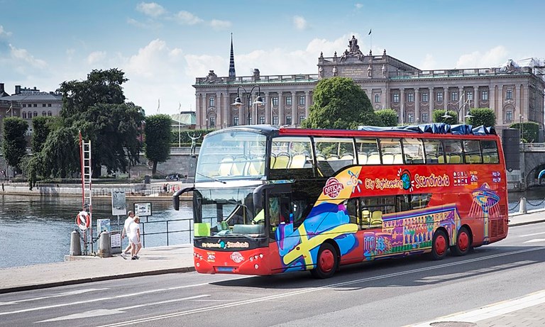 Red City Sightseeing bus drives past the Parliament House in Stockholm.