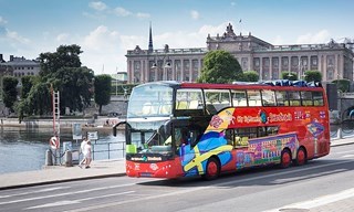 Red City Sightseeing bus drives past the Parliament House in Stockholm.