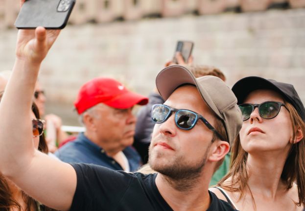Guests onboard Stromma's canal tour looking at sights; one is taking photos with his phone.