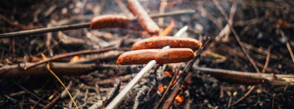 BBQ over fire in the forest - grilling hot dogs