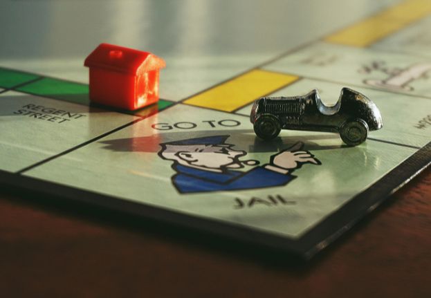 Monopoly board with a red hotel piece and a silver car token on the 'Go to Jail' space.