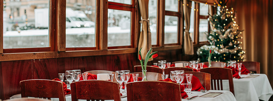 A set dining room aboard M/S Angantyr with a decorated Christmas tree in the background