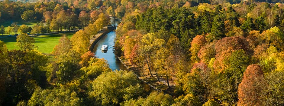 Aerial view of an autumnal Djurgården with a sightseeing boat in the canal