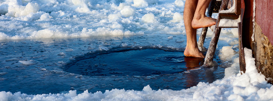 A hole in the ice and two legs climbing down a ladder for a swim