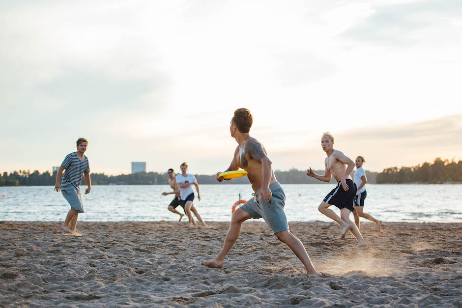 Group of people playing fresbee at a beach on a summer night